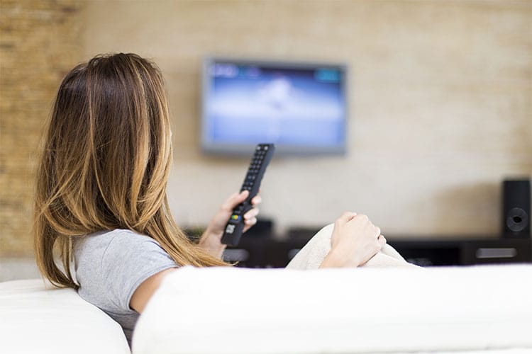 Frau auf Sofa mit Fernbedienung